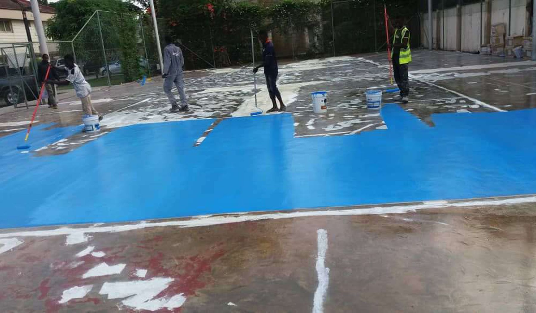 Coloured deck coating being applied around a pool area