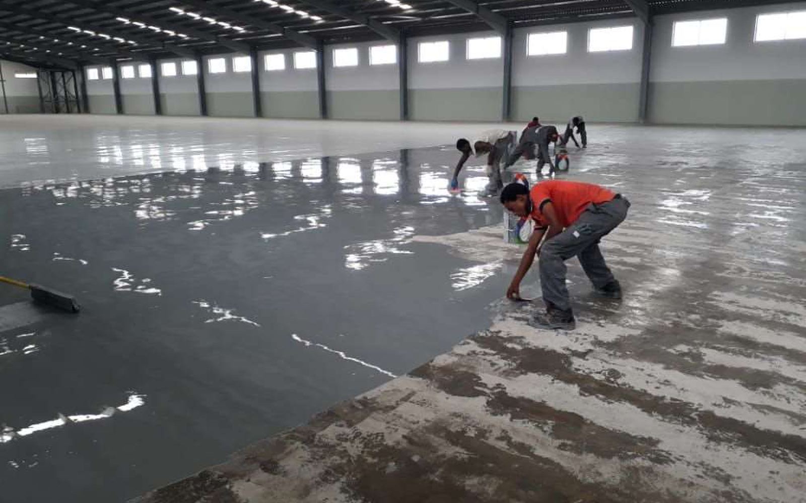 SD Aqua Proof crew applying floor coating in a large industrial warehouse